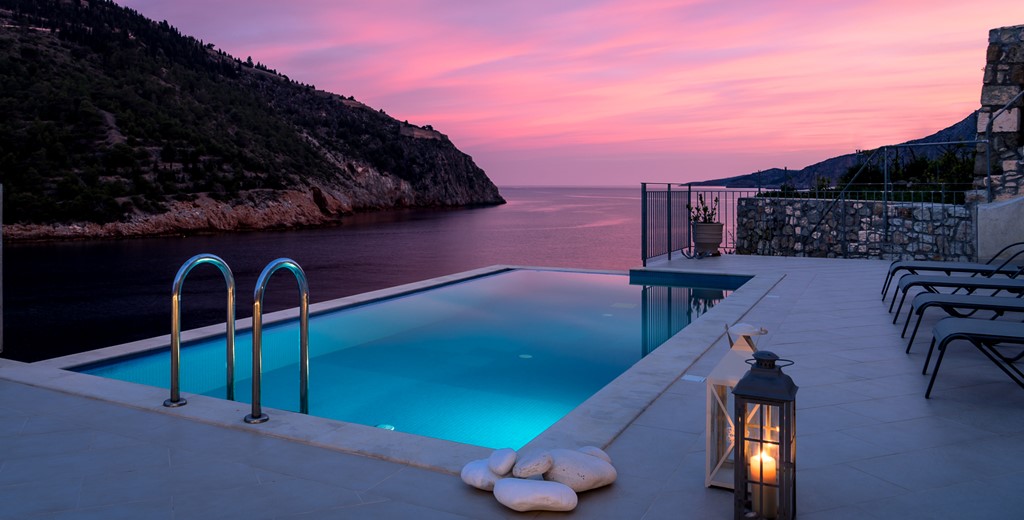Sunset, lanterns and a lit infinity pool ready for an evening swim at Villa Plori, Assos, Kefalonia