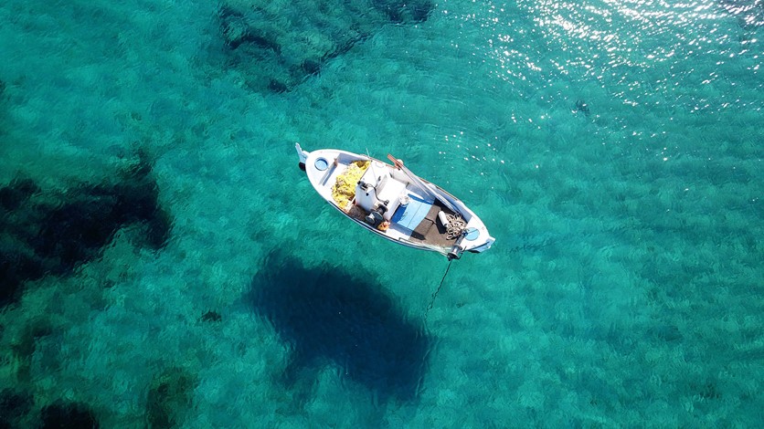 Traditional fishing boat floating in crystal clear waters off the coast of Kefalonia, Greek Islands
