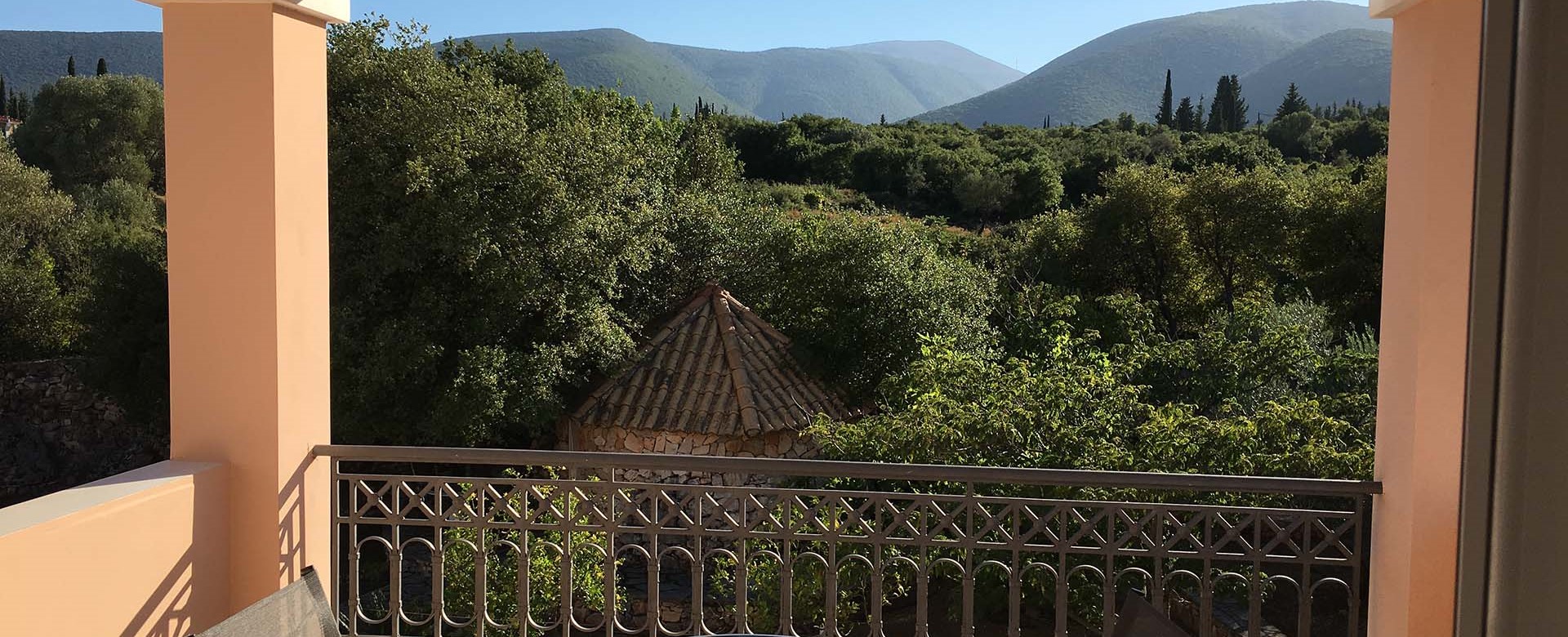 Share a holiday drink with mountain views on the veranda at Casa Angela, Melissani Apartments, Karavomilos, Kefalonia, Greek Islands