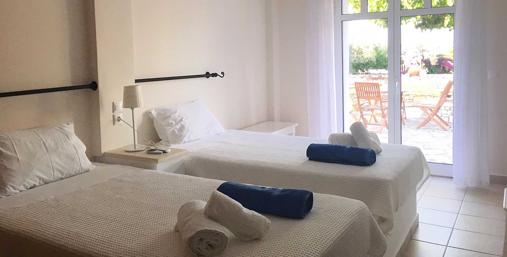 Bedroom with single beds and French doors opening onto the patio at Casa Elena, Melissani Apartments, Karavomilos, Kefalonia, Greek Islands
