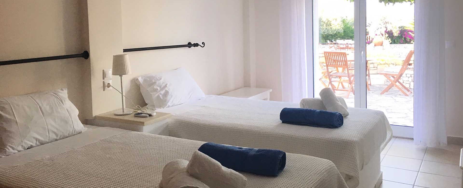 Bedroom with single beds and French doors opening onto the patio at Casa Elena, Melissani Apartments, Karavomilos, Kefalonia, Greek Islands