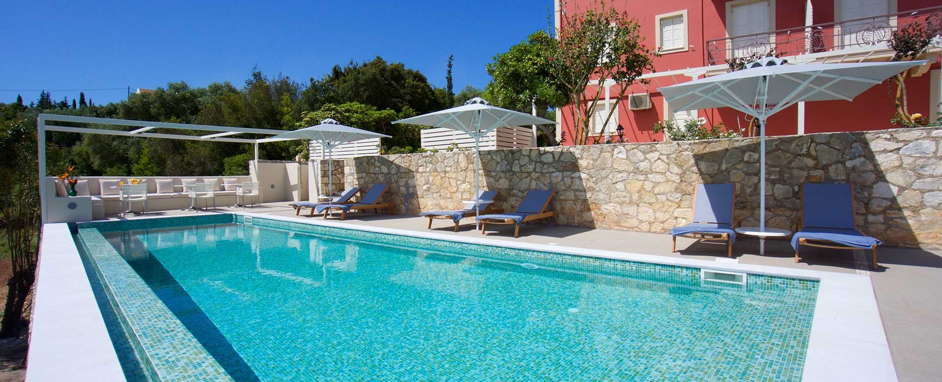Pool and sun beds ready for a long holiday sunbathing outside Magnolia Apartments, Fiscardo, Kefalonia, Greek Islands