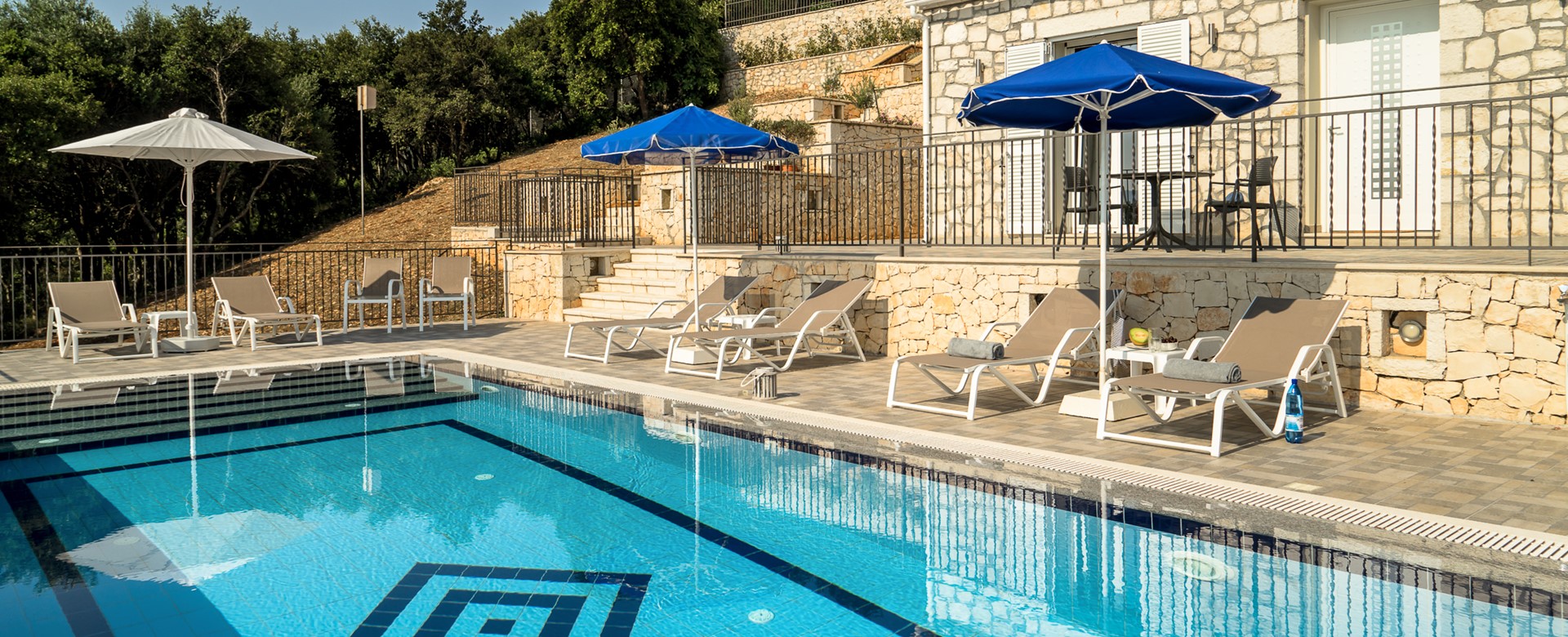 Family friendly poolside setting with loungers and umbrellas at Villa Gionis Fiscardo, Kefalonia, Greek Islands