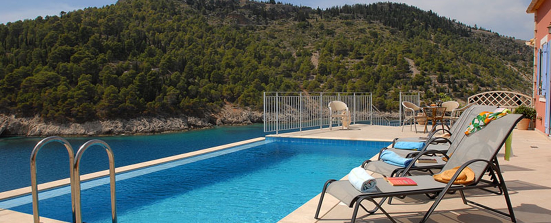 Infinity pool, sun loungers and view of the hill outside Villa Panorama, Assos, Kefalonia
