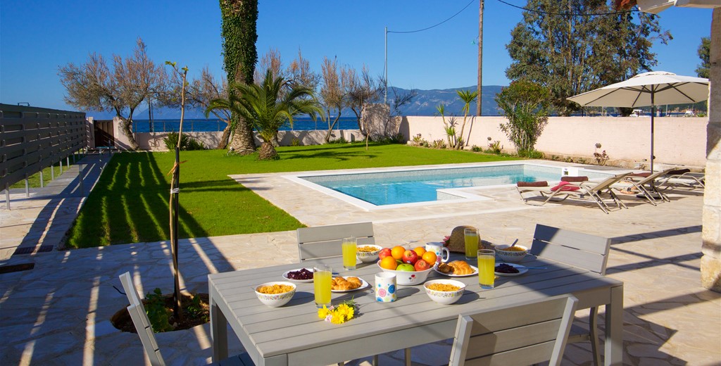 Outside dining with a view across manicured gardens and pool at Villa Theano, Sami, Kefalonia, Greek Islands