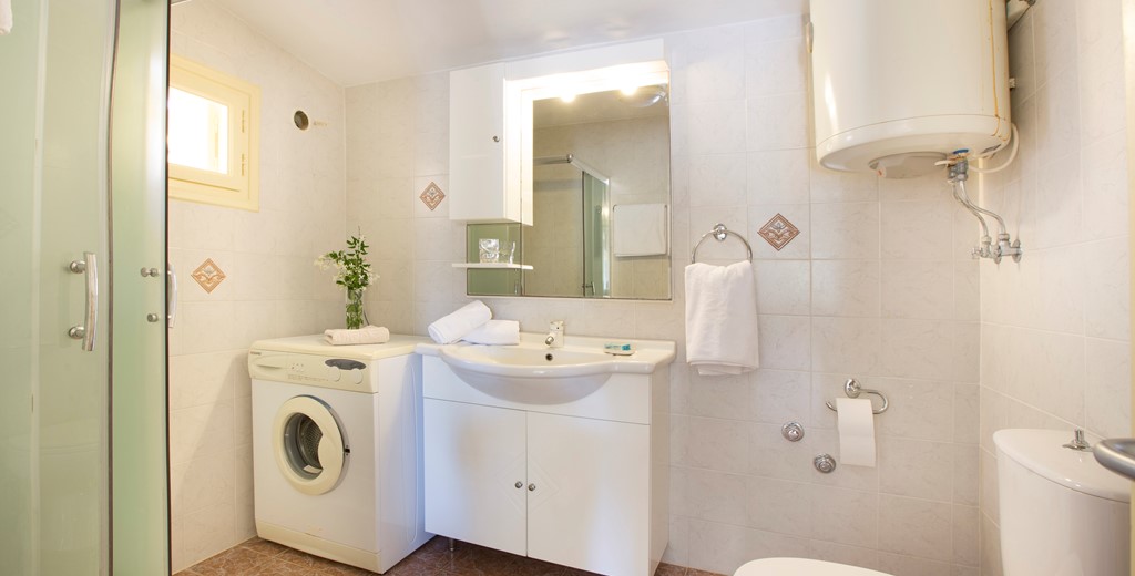 Bathroom with shower and washing machine inside Lemoni Cottage, Fiscardo, Kefalonia