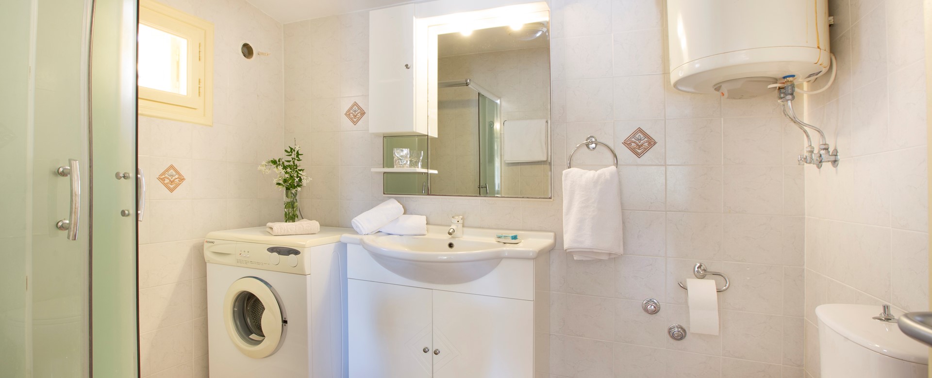 Bathroom with shower and washing machine inside Lemoni Cottage, Fiscardo, Kefalonia