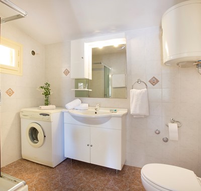 Bathroom with shower and washing machine inside Lemoni Cottage, Fiscardo, Kefalonia