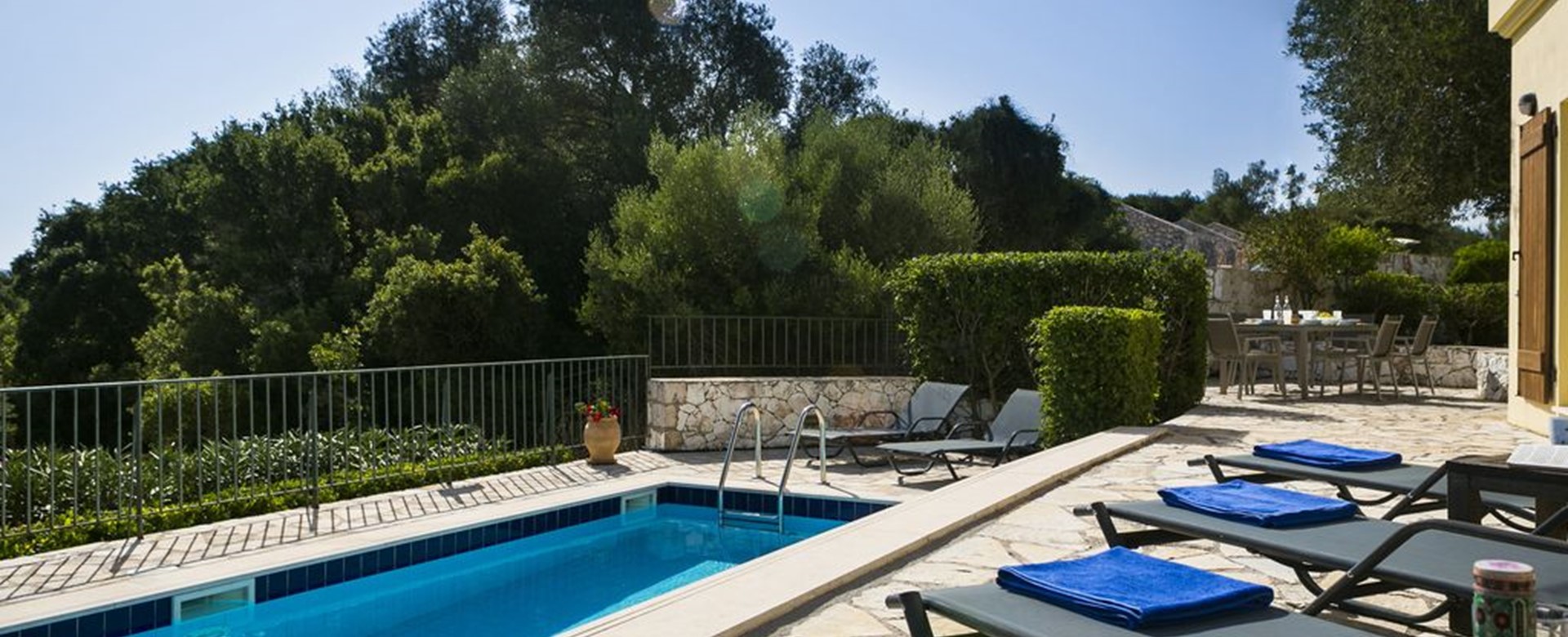 Sun beds and pool sorrounded by lush green trees in Villa Cypress, Fiscardo, Kefalonia, Greek Islands